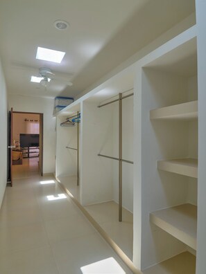 A corridor with built-in closets, a ceiling fan, and recessed lighting.
