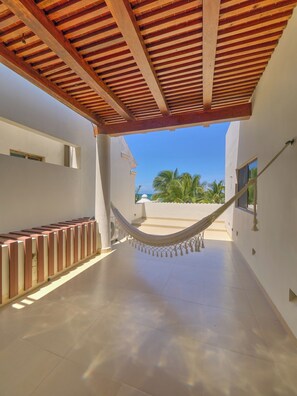 A covered outdoor area with a hammock, tiled floor, and a view of the sea. - Casa Macabi - Yucatan Home Rentals (Chicxulub Puerto)