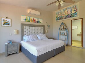 A bedroom with a large bed, a ceiling fan, an air conditioning unit, and artwork on the walls. - Casa Macabi - Yucatan Home Rentals (Chicxulub Puerto)