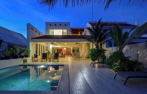 Een modern huis met een zwembad, een terras en een goed verlichte patio.