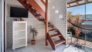 A staircase with a wooden finish, a white brick wall, a mounted television, and a potted plant.