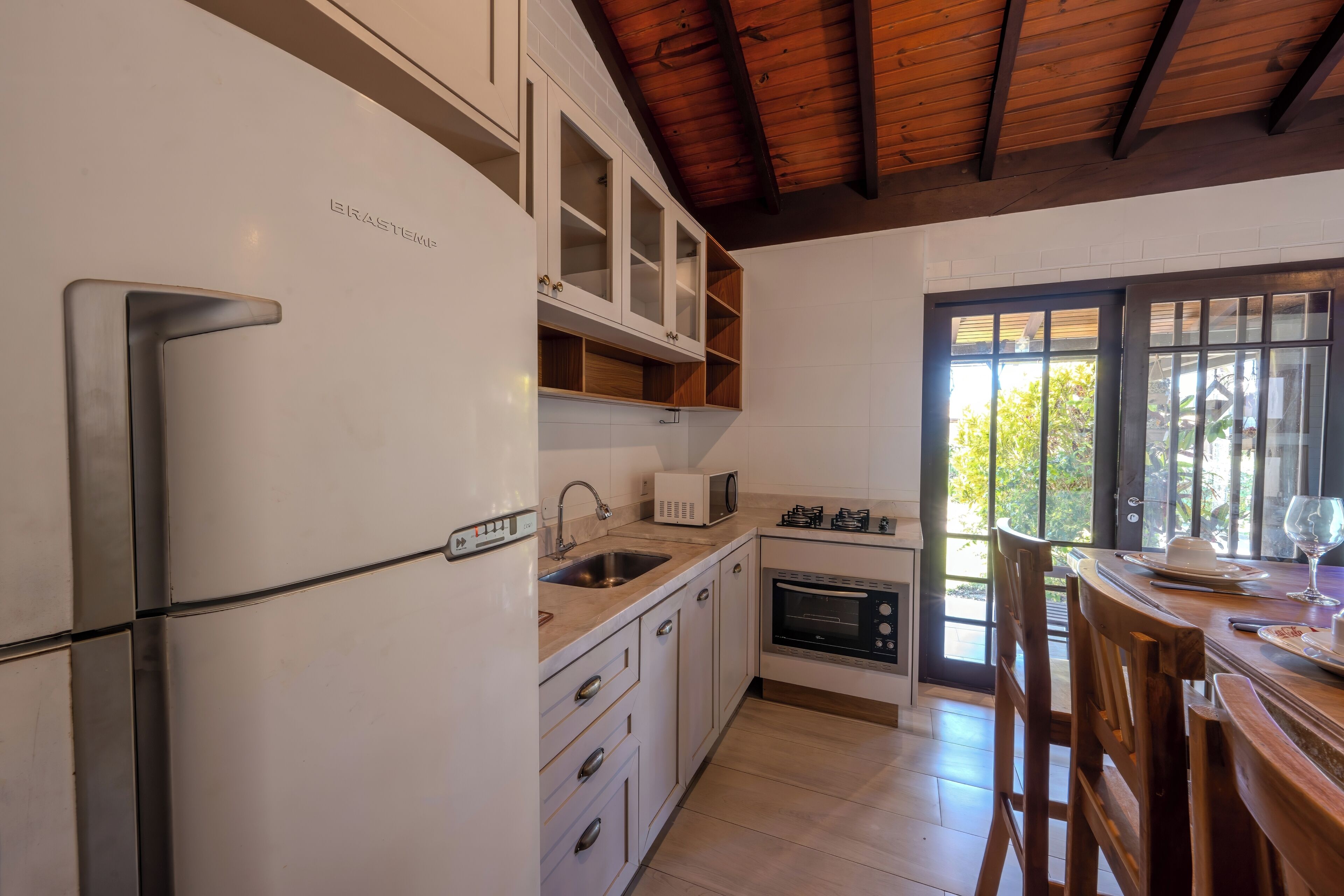A modern kitchen with white cabinets, a stainless steel refrigerator, a microwave, and an oven.
