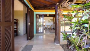 A hallway with wooden floors, a door, and a plant area with hanging baskets.