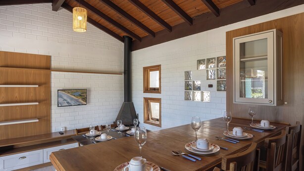A dining area with a wooden table set for four, white brick walls, and a wooden ceiling.