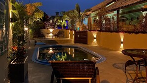 A pool area with lounge chairs, a small pool, and a building with a tiled roof.