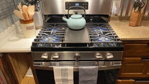 A kitchen with a stainless steel stove, a kettle, and wooden utensils in a container. - Historic and unique home on the hill, blocks away from the Marietta Square. (Marietta)