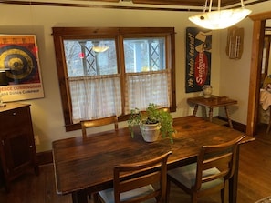 Een houten eettafel met vier stoelen, een plant in pot en een raam met gordijnen.
