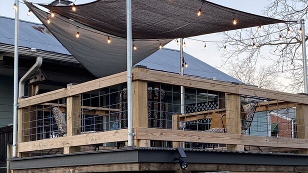 A wooden deck with a metal railing, a large shaded area with string lights, and a solar panel on the roof. - Historic and unique home on the hill, blocks away from the Marietta Square. (Marietta)