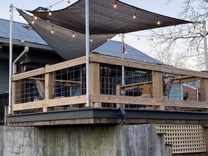 A wooden deck with a metal railing, a large shaded area with string lights, and a solar panel on the roof. - Historic and unique home on the hill, blocks away from the Marietta Square. (Marietta)