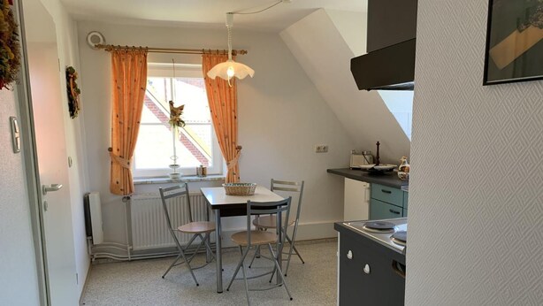 A compact kitchen with a dining table, chairs, and a hanging light fixture. - Wiesenblick - Idyllic and quiet location, family-friendly (Grube)