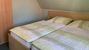A single bed with a wooden headboard, a small bedside table with a lamp, and a wall-mounted picture. - Wiesenblick - Idyllic and quiet location, family-friendly (Grube)