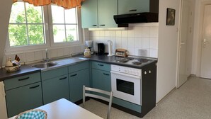 A compact kitchen with teal cabinets, a white stove, and a window with a curtain. - Wiesenblick - Idyllic and quiet location, family-friendly (Grube)