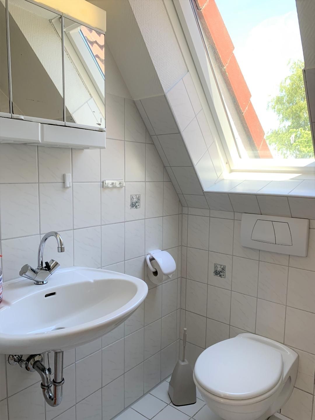 Een badkamer met een witte wastafel, toilet en een raam met uitzicht.