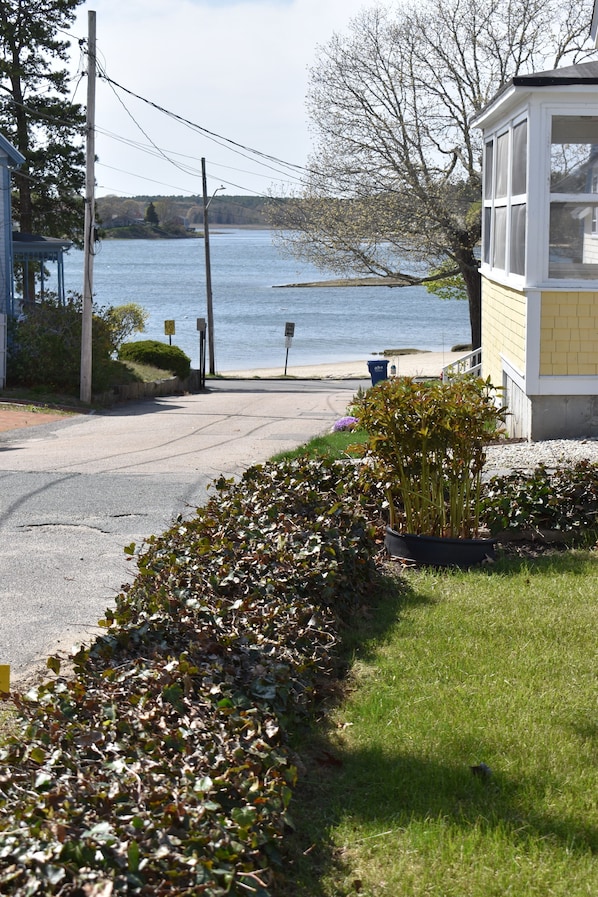 A waterfront property with a covered porch, a grassy area, and a view of the lake.
