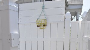 Una cerca de madera blanca con una jaula amarilla colgada.