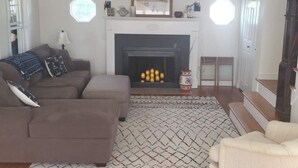 Una sala de estar con chimenea, sofá y alfombra.