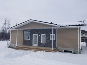 Une maison à deux étages avec une façade en pierre, un porche à l’avant et un garage.