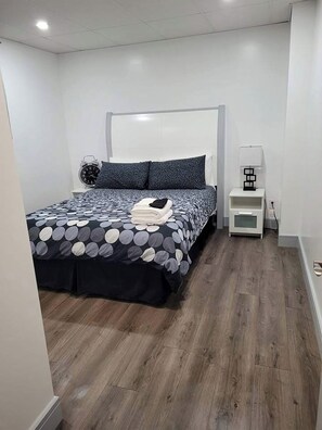 Une chambre à coucher avec un lit, une table de chevet, une lampe et une horloge.