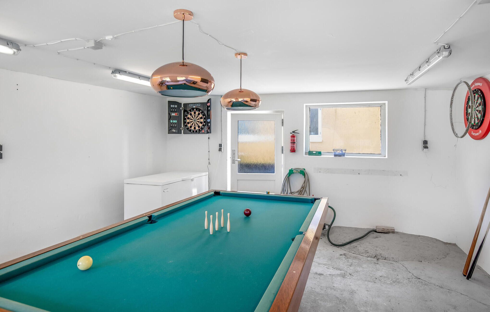 A pool table with balls, two dartboards, and a dartboard with a dart ring.