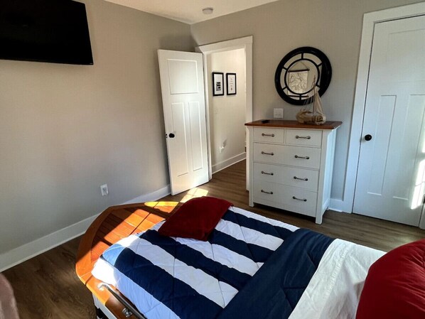 A bedroom with a bed, a dresser, a mirror, and a door.