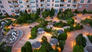 Vista aérea de un patio de hotel con jardines ajardinados, zonas de estar y una fuente central.