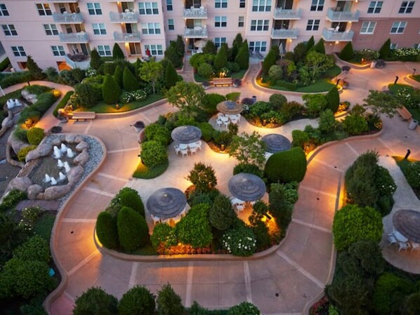 Vista aérea de um pátio de hotel com jardins bem cuidados, áreas de estar e um recurso aquático central.