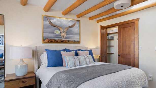 Ein Schlafzimmer mit einem Bett, einem Nachttisch, einer Lampe, einer Holztür und einem Bild an der Wand.