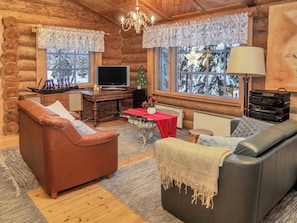 A cozy log cabin interior with a brown leather sofa, a gray sofa, a wooden desk with a computer, and a television. - Vacation home Koivu by Interhome (Kuusamo)
