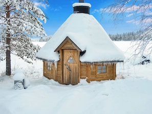 A wooden cabin with a snow-covered roof, surrounded by a snowy landscape and trees. - Vacation home Koivu by Interhome (Kuusamo)