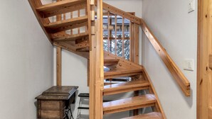 A wooden staircase with a simple design, a sewing machine, and a small table in a room with plain walls.