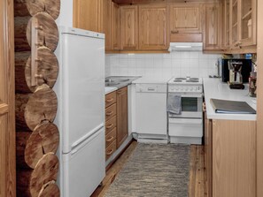 A compact kitchen with wooden cabinets, a white refrigerator, a stove, and a sink. - Vacation home Koivu by Interhome (Kuusamo)