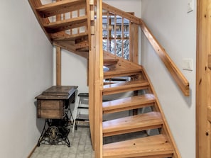 Un escalier en bois avec une rampe en métal, une machine à coudre ancienne et une échelle.