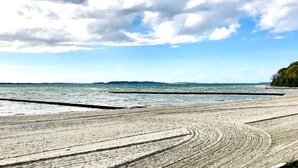 A beach with a wide sandy shore and a calm sea under a partly cloudy sky. - Modern vacation apartment with balcony, sea view - Ferienresidenz Zwei BoddenFeWo 1-5 (Lietzow)