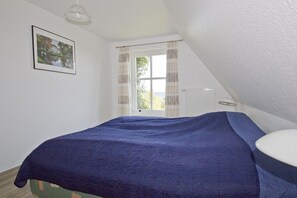 A bedroom with a bed, a window with curtains, a radiator, and a picture on the wall. - Gutshof Ostseeblick - beachfront idyll by the sea, private bathing area, beach chair (Putbus)