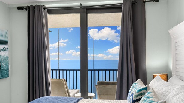 Ein Hotelzimmer mit Bett, Meerblick und Balkon mit Stühlen.