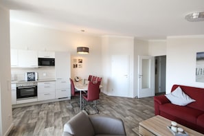 A modern apartment with a kitchen, dining area, and living room. - With a view of the sea and a balcony, access to the pool and sauna - Sea View Apartment 66 - (Göhren)