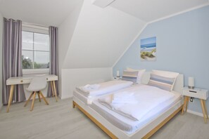 A bedroom with a bed, a desk, and a chair. - Vacation apartment with sea view and garden use - Haus Inselwind FeWo MEERduft - (Gager)