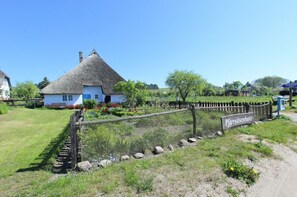 A traditional thatched-roof house with a sign reading "Pfarrwitwenhaus" in front.