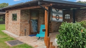 A small brick building with a tiled roof, a wooden porch, and a blue chair outside. - Stunning apartment in Rankwitz/ OT Suckow (Rankwitz/ OT Suckow)