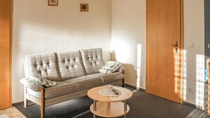 A cozy room with a plaid sofa, a small round table with a remote control, and two framed pictures on the wall. - Stunning apartment in Rankwitz/ OT Suckow (Rankwitz/ OT Suckow)