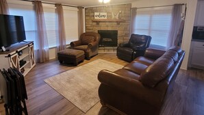 A living room with a fireplace, leather sofas, a television, and a wooden cabinet. - The DW - Spacious and Cozy (Columbia)