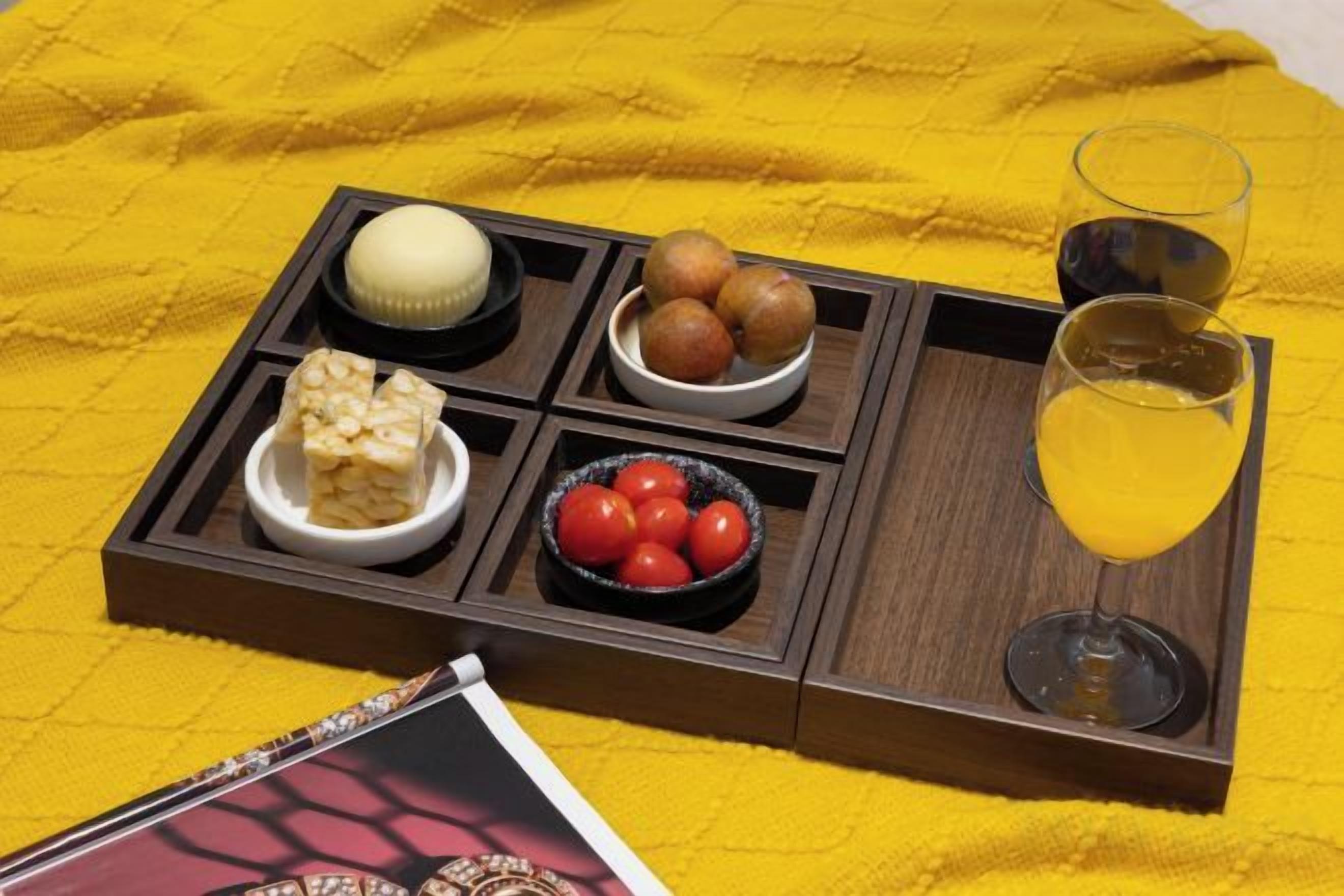 A tray with various food items and a glass of drink on a yellow cloth.