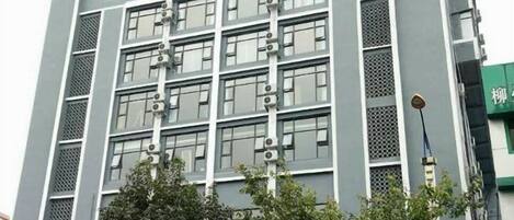 A multi-story building with a modern architectural design, featuring a series of windows and air conditioning units on the facade.