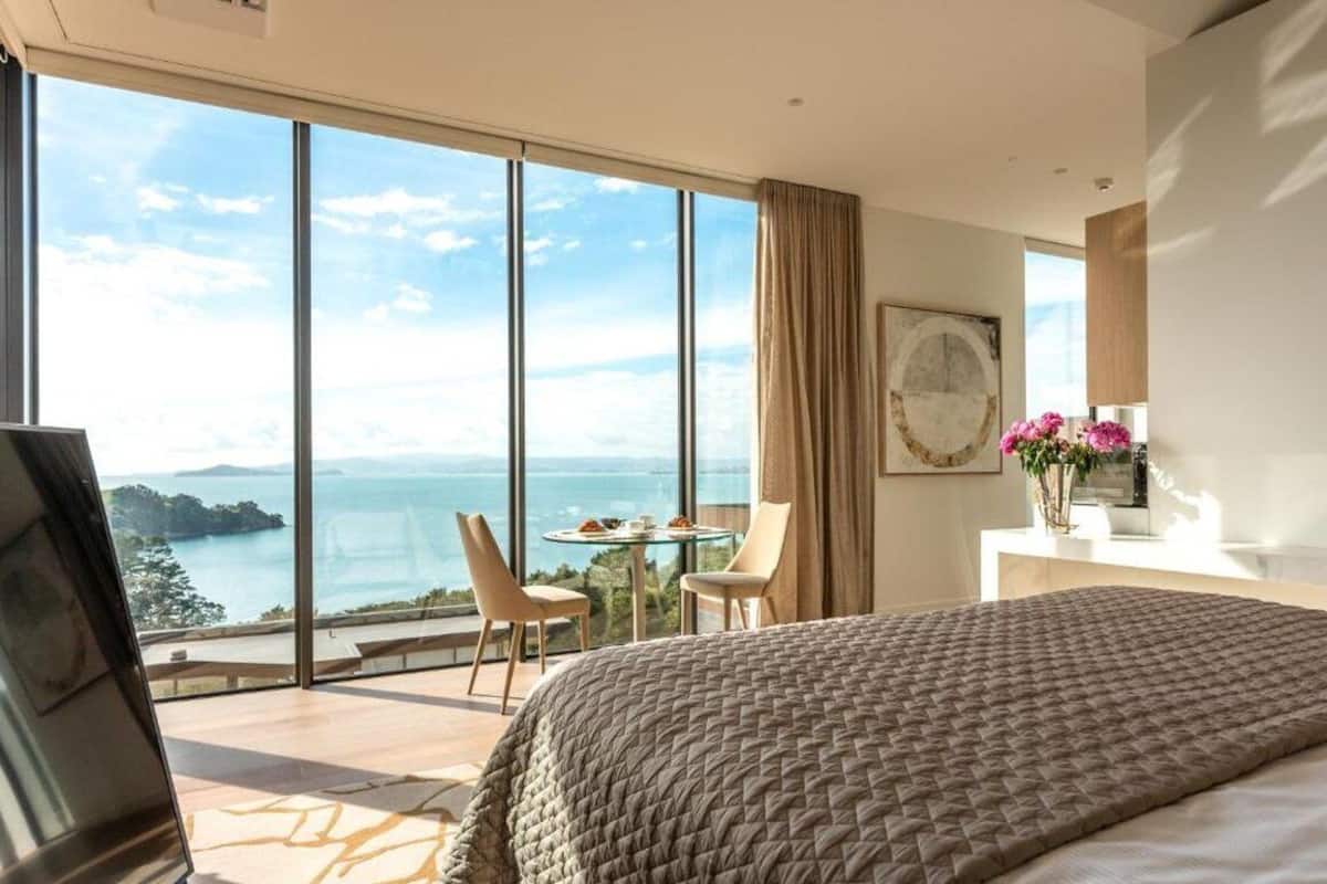 Ein Schlafzimmer mit einem großen Bett, Meerblick, einem Esstisch mit Stühlen und einem Bild an der Wand.