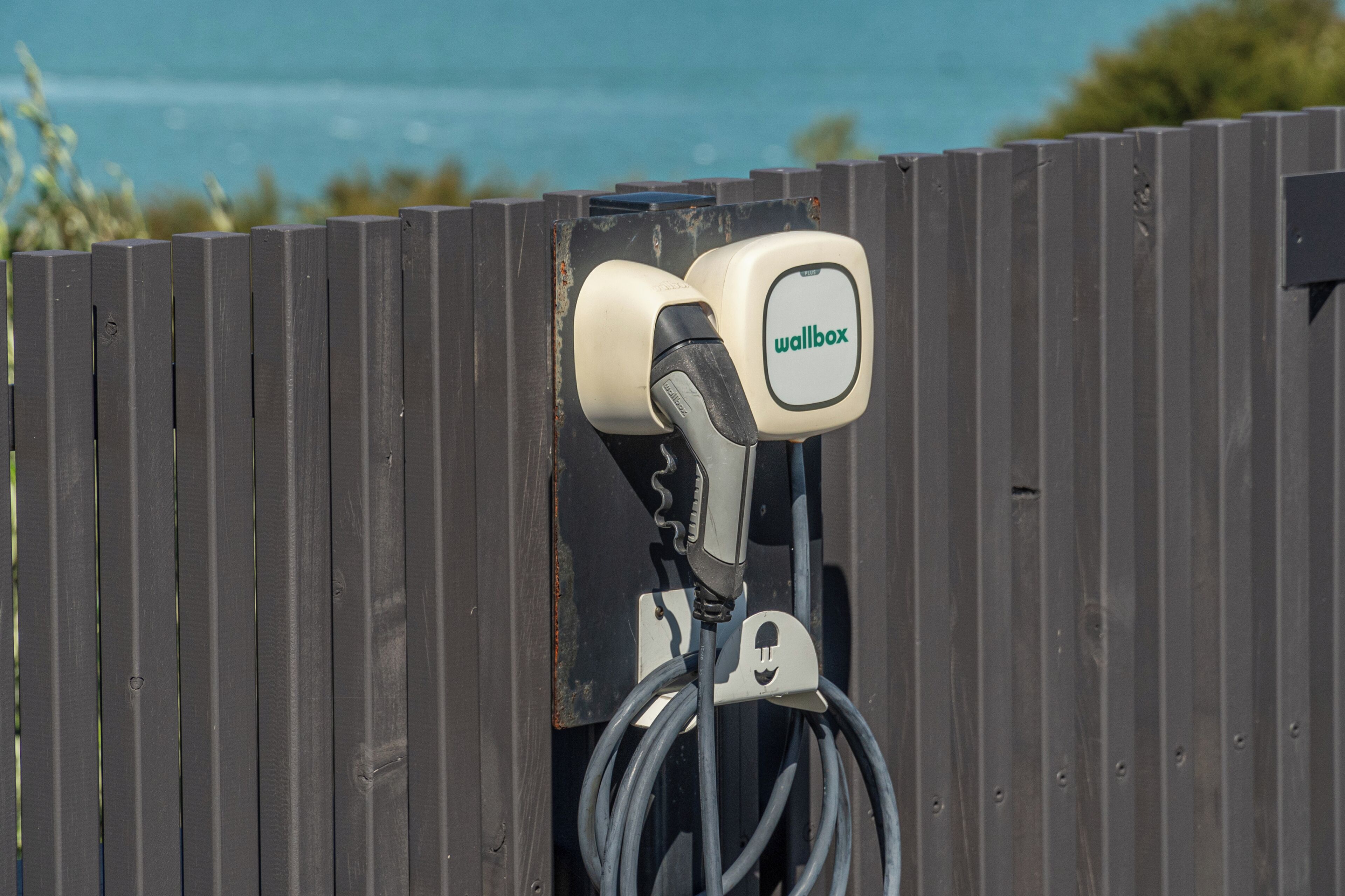 Cargador de pared con etiqueta que dice 'wallbox' adherida a una valla de madera.