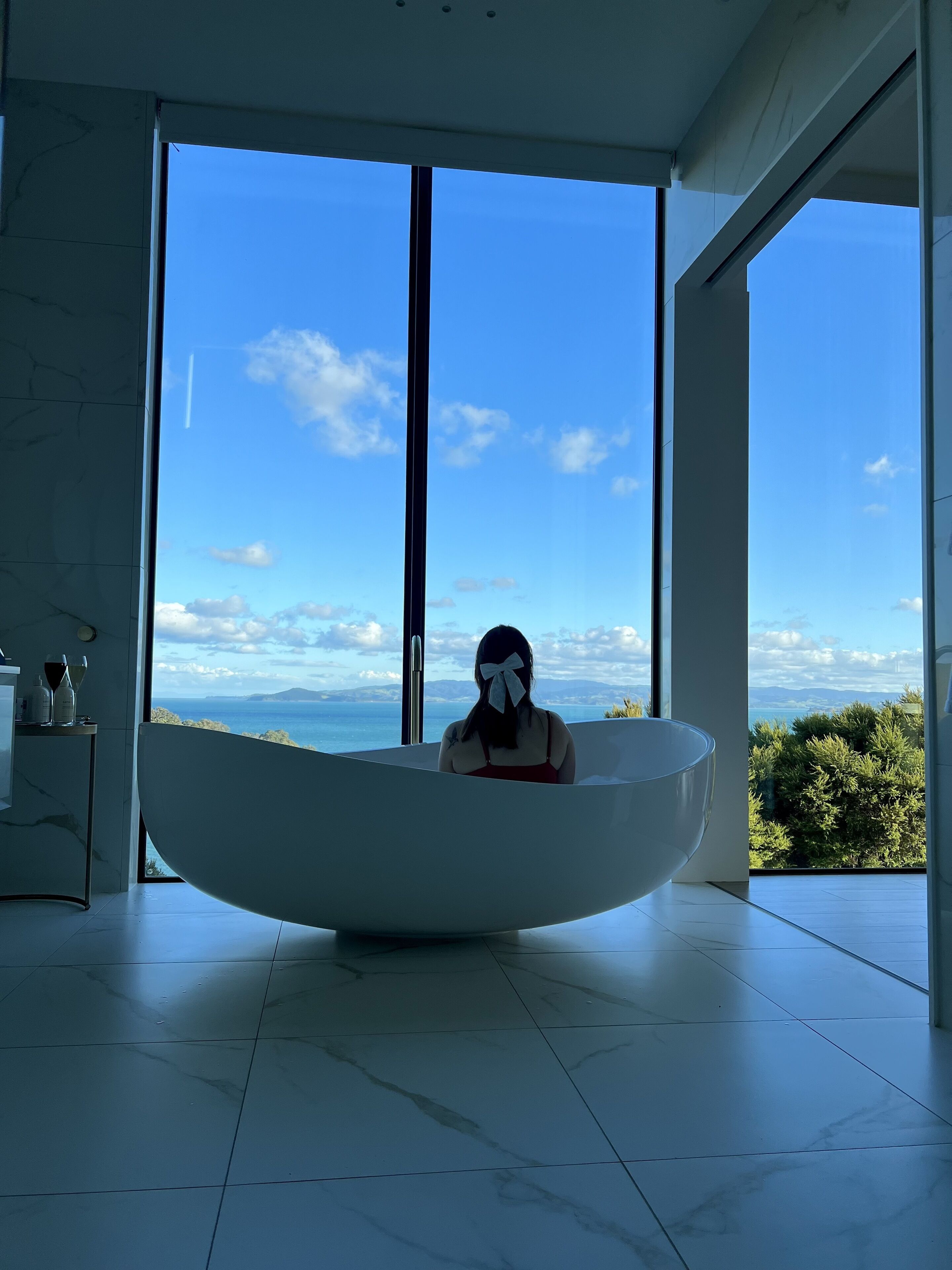 A modern bathroom with a large bathtub, a view of the sea, and a minimalist design.