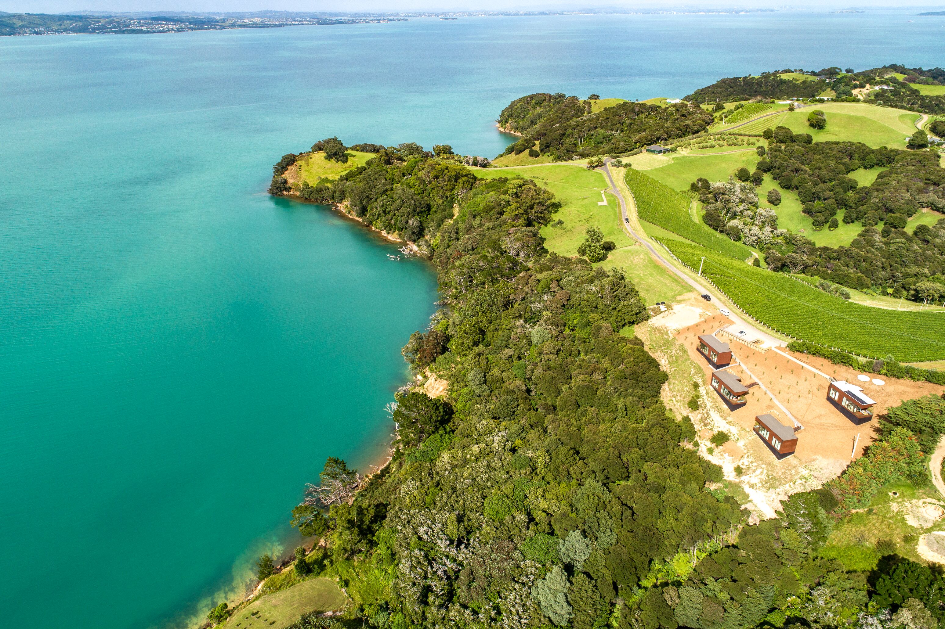 An aerial view of a coastal property with a golf course, a sandy beach, and several buildings.