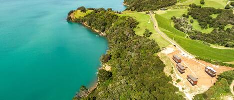 An aerial view of a coastal property with a golf course, a sandy beach, and several buildings.