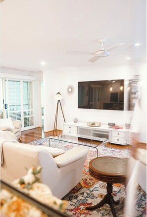 Relax in a spacious living room with a large flat-screen TV, comfortable sofa, and decorative rug.