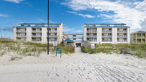 Hotel frente a la playa con una arena dorada, edificios de dos plantas y cielo despejado.